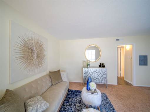 a living room with a couch and a mirror at Villas del Tesoro Apartments, Dallas, TX, 75228