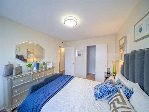 a bedroom with a large bed and a mirror at Villas del Tesoro Apartments, Dallas, TX