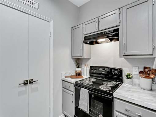 a kitchen with white cabinets and a black stove