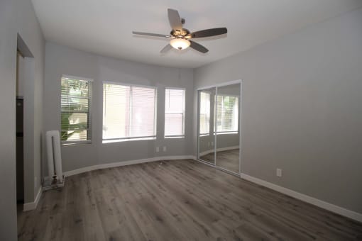 an empty living room with a ceiling fan and windows