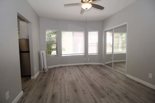 an empty living room with a ceiling fan and windows