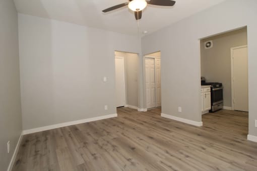 a living room with white walls and a ceiling fan