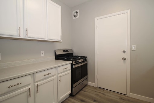 a kitchen with white cabinets and a stove and a door