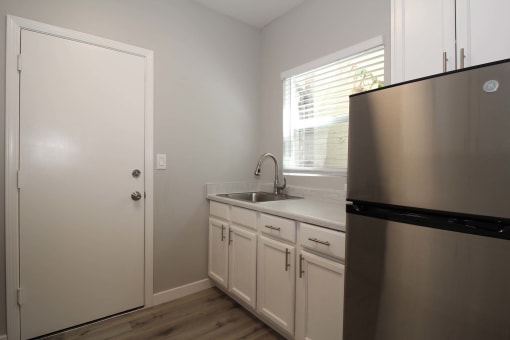 a kitchen with white cabinets and a stainless steel refrigerator