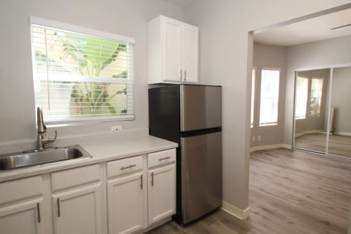 a kitchen with white cabinets and a stainless steel refrigerator