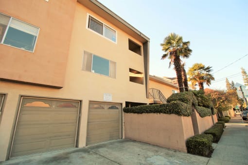 a building with a garage and palm trees in front of it