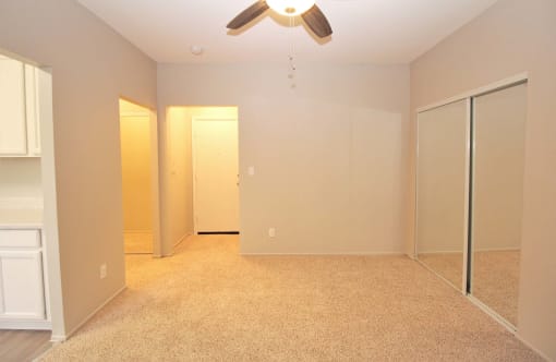 a empty bedroom with a ceiling fan and mirrored closet