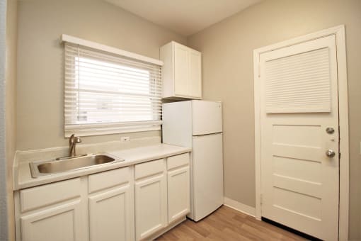 a kitchen with white cabinets and a sink and a refrigerator