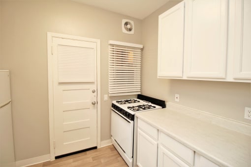 a kitchen with white cabinets and a stove and a door