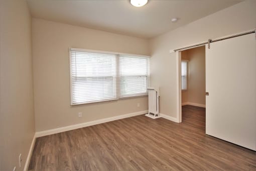 an empty living room with wood floors and white walls