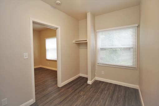 a bedroom with a closet and a window and wood flooring