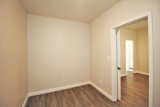 a empty room with wood flooring and a door to a hallway