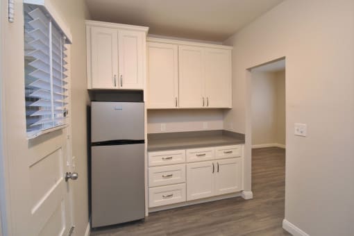 a kitchen with white cabinets and a stainless steel refrigerator