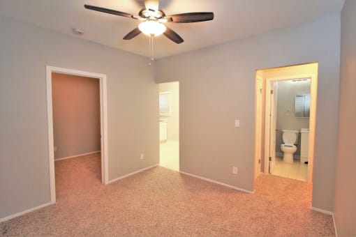 an empty room with a ceiling fan and a bathroom