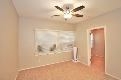 a bedroom with a large window and a ceiling fan