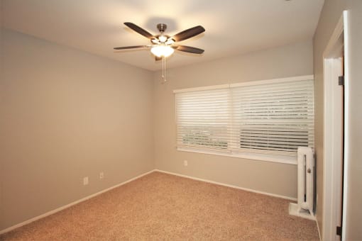 a bedroom with a large window and a ceiling fan