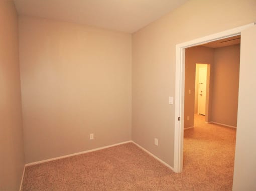 a empty room with a carpeted floor and a door to a hallway