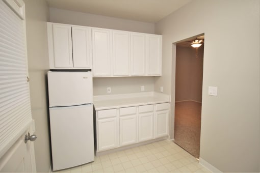 a kitchen with white cabinets and a refrigerator