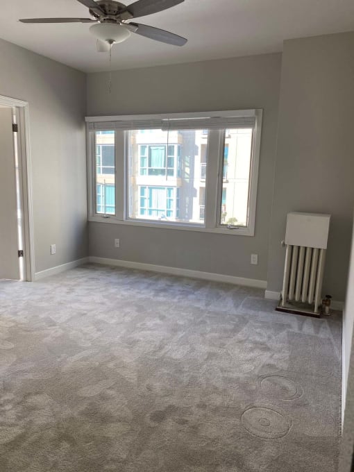 an empty living room with a ceiling fan and a window