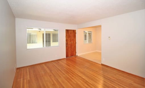an empty living room with hard wood flooring and a window