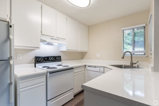 an empty kitchen with white appliances and white counter tops