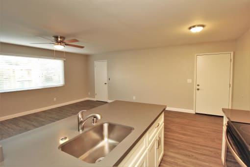 an empty kitchen with a sink and a ceiling fan