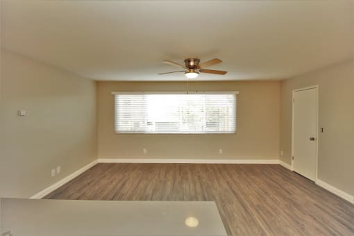 an empty living room with a ceiling fan and a window