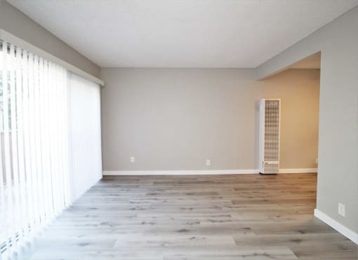an empty living room with a large window and wood floors