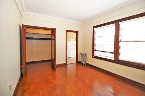 an empty living room with wood floors and a door to a closet