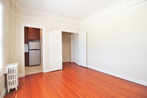an empty living room with wood floors and white walls
