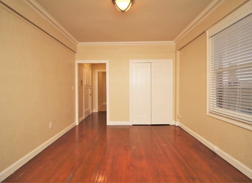 an empty living room with wood floors and a window