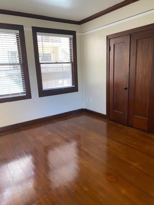 a living room with a hard wood floor and two windows