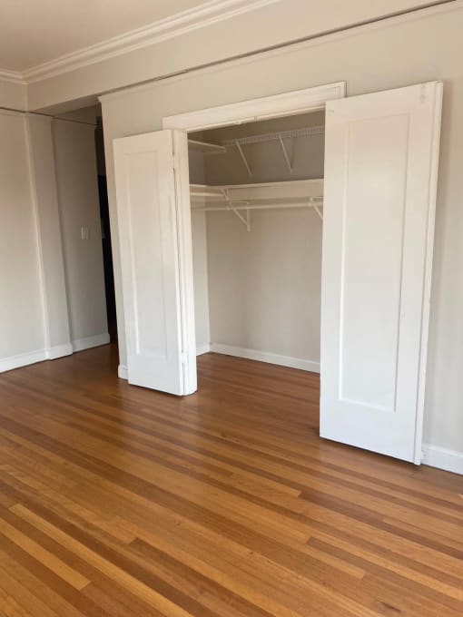 a living room with a hard wood floor and an open closet