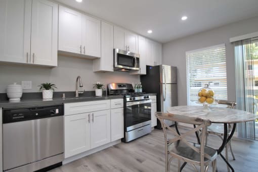 a kitchen with white cabinets and a table with chairs