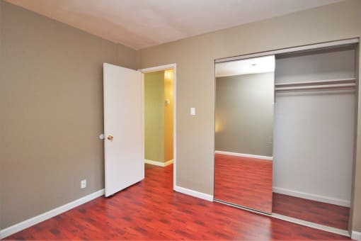 a bedroom with a hard wood floor and a closet