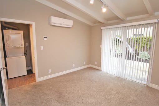 an empty living room with a laundry room and a door to a patio