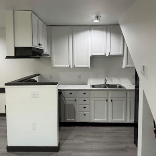 A kitchen with white cabinets and a black countertop.