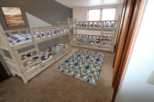 a bunk bed room with two bunk beds and a rug