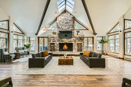 A large, open-concept living room with a stone fireplace and skylight.
