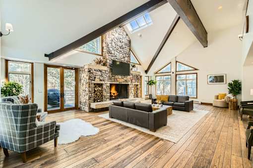 A modern living room with a stone fireplace and wooden floors.