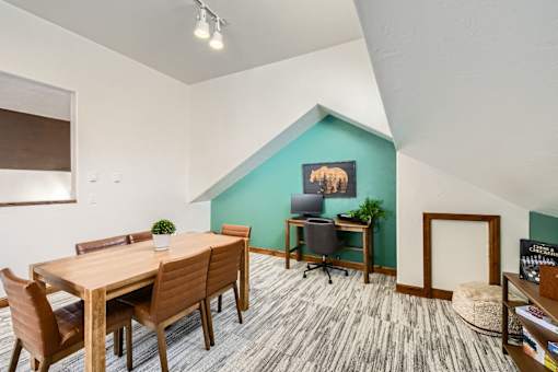 A room with a wooden table and chairs, a green wall, and a picture of a bear on the wall.