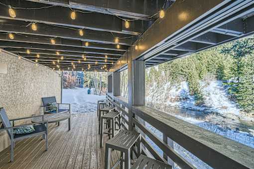 A wooden deck with a table and chairs overlooking a snowy landscape.