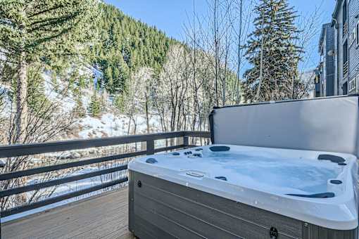 A hot tub is on a deck with a snowy mountain in the background.