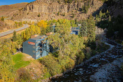 A building with a blue roof is situated in a valley with a river running through it.