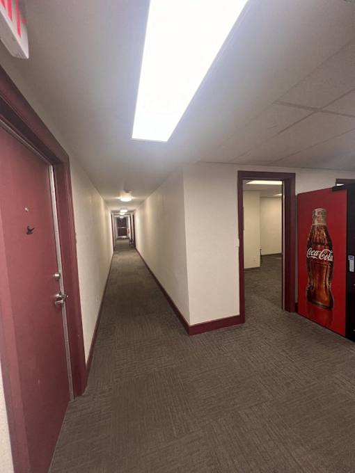 A long hallway with a Coca-Cola machine at the end.