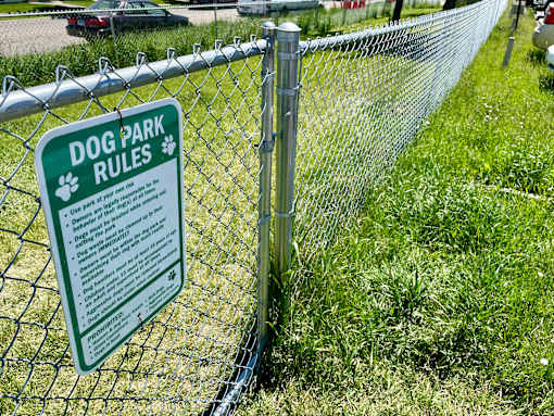 a dog park rules sign on a chain link fence