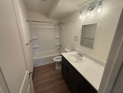A white sink is on a counter under a mirror in a small bathroom.