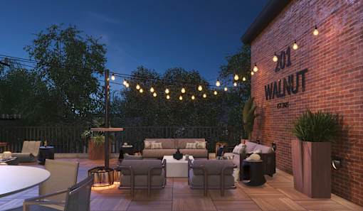 A patio area with tables and chairs is illuminated by string lights.