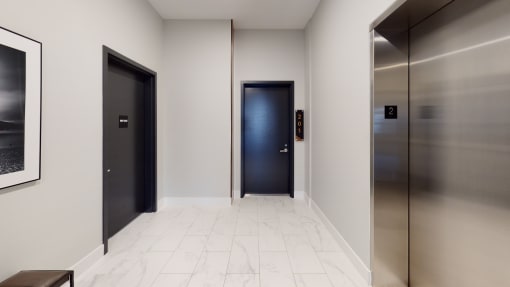 a hallway with three elevators and a black door