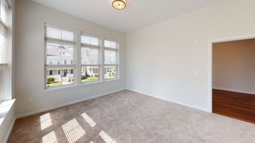 an empty living room with large windows and carpet